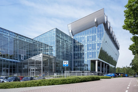 Modern glass building with a blue sky and trees in the background